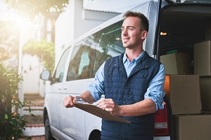 man standing in front of commercial van holding a clipboard